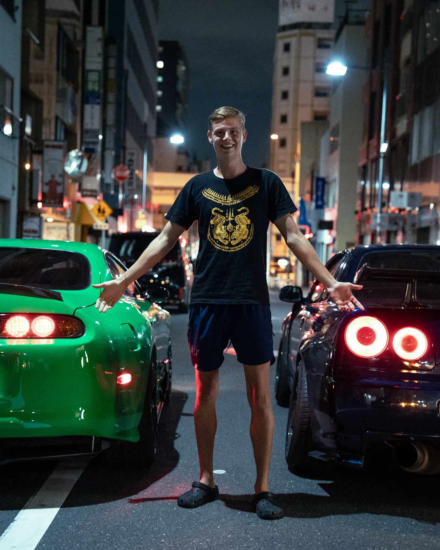 Guest between a green Supra and a blue R34 Skyline at night