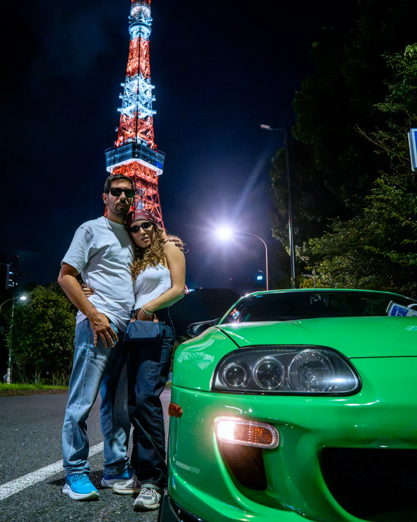 Guests beside a green Supra with Tokyo Tower behind them
